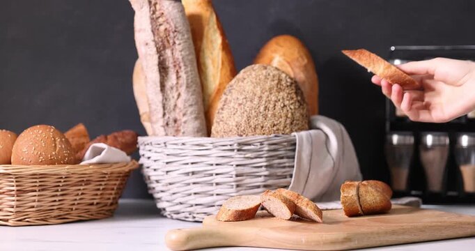 Woman taking fresh bread slice at white countertop, closeup