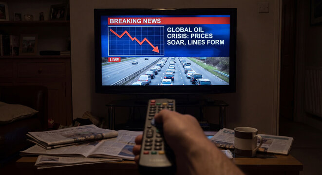 Man watching television news about global oil crisis while holding a remote