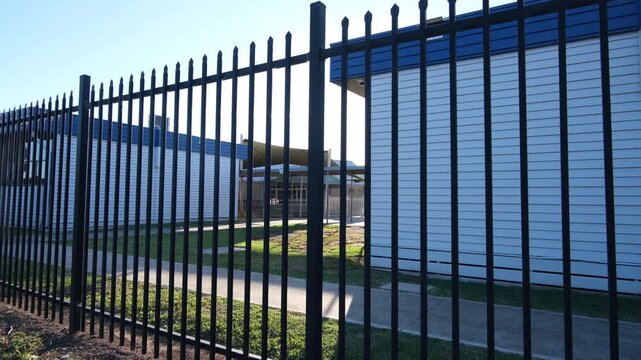 Black steel security fencing at a public primary school in Melbourne, Victoria, Australia, with modular classroom facility buildings behind. Child safety, infrastructure of Australian public education