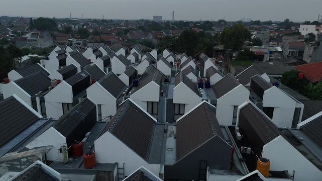 Aerial view of modern minimalist housing complex with symmetrical white walls and dark grey roofs in urban residential area