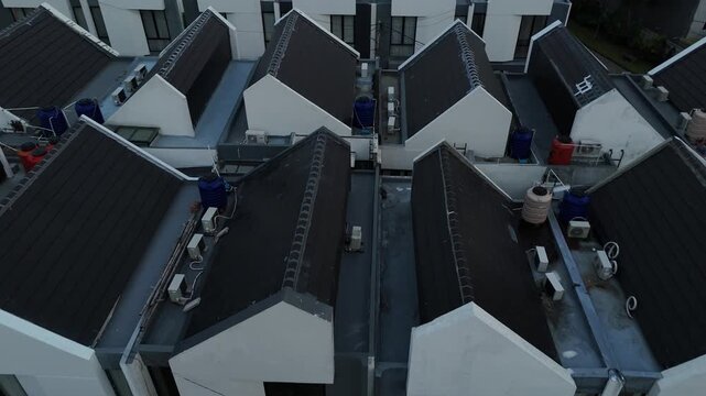 Aerial drone view of modern minimalist townhouse complex with symmetrical gabled roofs in Jakarta residential area