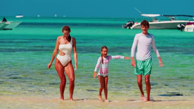 A mother with her children, a young daughter and a teenage son, dance in the crystal clear azure water of the Indian Ocean while having fun on vacation