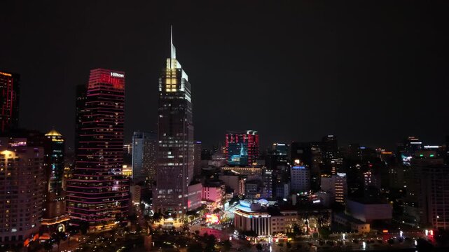 Vietnam, Ho Chi Minh Saigon Skyline Night Glowing Neon Lights, Illuminated Skyscrapers And Busy Boulevards, Aerial Pan Captures Rooftop Signs, Traffic Streaks, Warm Street Glows And Vibrant