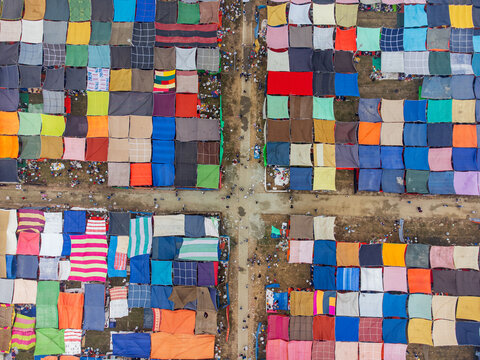 Tongi, Bangladesh - 31 January 2025: Aerial view of colorful square tents and canopies arranged in a grid pattern with people walking along the dirt paths during a large gathering.