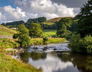 Obraz premium A serene countryside scene featuring a flowing river, green fields, trees, and rolling hills beneath a cloudy sky