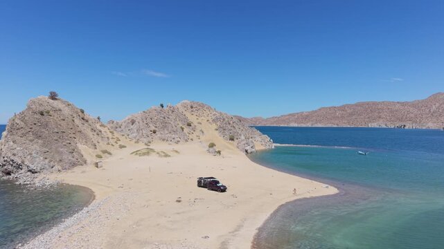 Aerial views show SUV and teardrop trailer camping on Punta Final island in Gonzaga Bay, Baja California, Mexico under clear skies.
