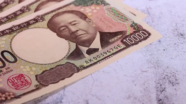 画面左にスライドして静止する複数の一万円札の映像