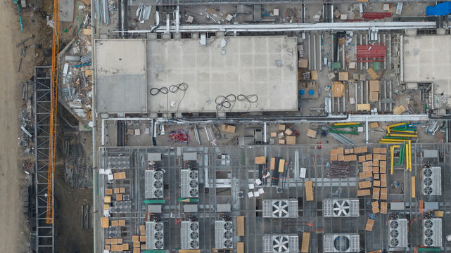 Tambon Khlong Tamru, Thailand - 11 March 2026: Aerial view of an industrial building roof under construction with HVAC units, colorful pipes, and building materials.