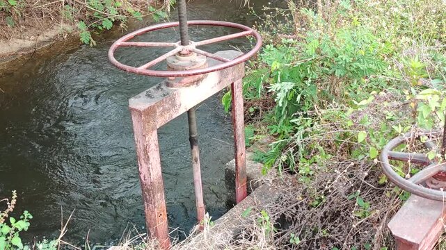 Manual irrigation sluice gate with handwheel and bevel gears in traditional canal