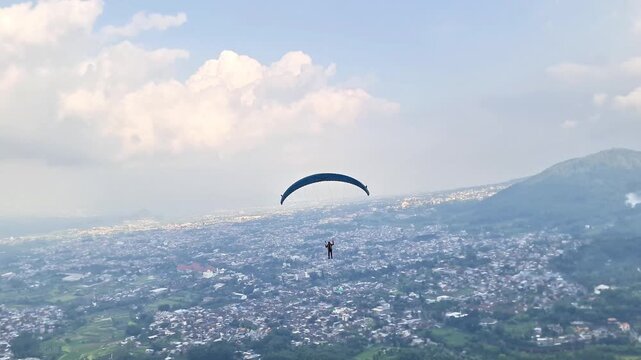Malang, Indonesia - 3 May, 2026: Licensed Paragliding Pilot Expertly Launching from Mountain Summit Edge