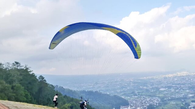 Malang. Infonesia - 3 May, 2026: Professional Athlete Taking Off for Paragliding Adventure over Scenic City Landscape