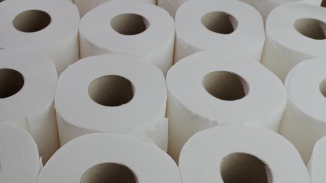 Rows of white toilet paper rolls arranged in perfect order on shop shelf.