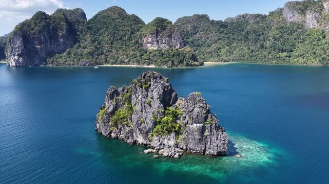 Surrounded by coral, rugged limestone islands rise from Bacuit Bay, El Nido. This area in the Philippines is a popular vacation destination due to its coral reefs, beaches, and limestone islands.