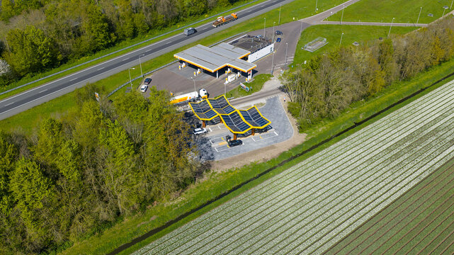 Bant, Netherlands - 21 April 2026: Aerial view of the Fastned charging station and Shell gas station next to a highway and white tulip fields in Flevoland.