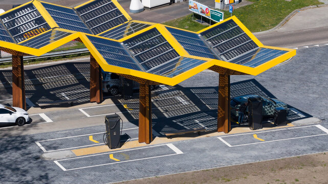 Bant, Netherlands - 21 April 2026: Aerial view of the Fastned Charging Station featuring a distinctive yellow solar-panel roof with electric cars parked at charging points.
