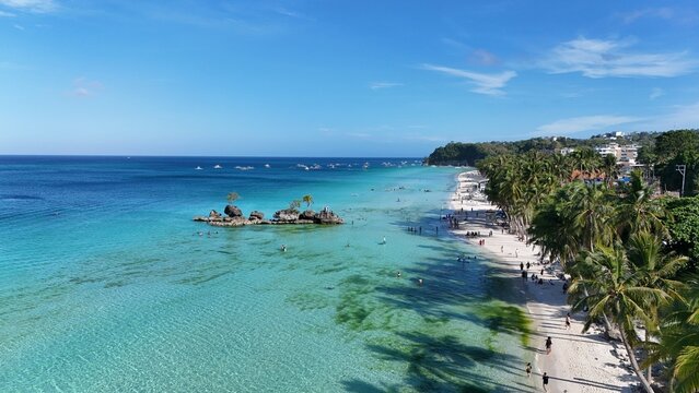 Malay, Philippines - 01 May 2026: Aerial view of Boracay Island featuring Willy's Rock, turquoise waters, white sand beach lined with palm trees and people under a clear blue sky.