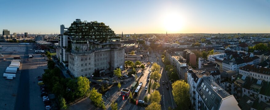 Hamburg, Germany - 01 May 2026: Aerial view of the St. Pauli Bunker with its lush green rooftop garden overlooking the Heiligengeistfeld and the city skyline during a clear sunset.