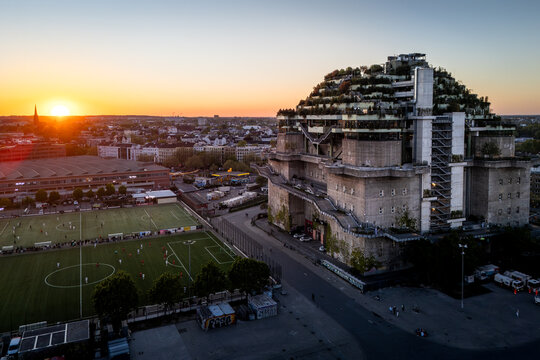 Hamburg, Germany - 01 May 2026: Aerial view of the green St. Pauli Bunker at Heiligengeistfeld during sunset, with a football pitch and the city skyline in the background.