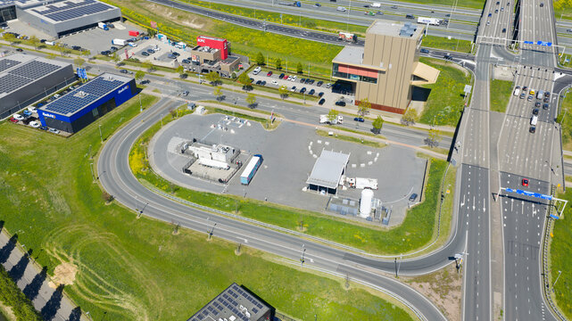 Utrecht, Netherlands - 29 April 2026: Aerial view of the LNG and hydrogen Tankstation Rolande featuring fuel pumps and designated parking spaces next to a busy road with passing vehicles.