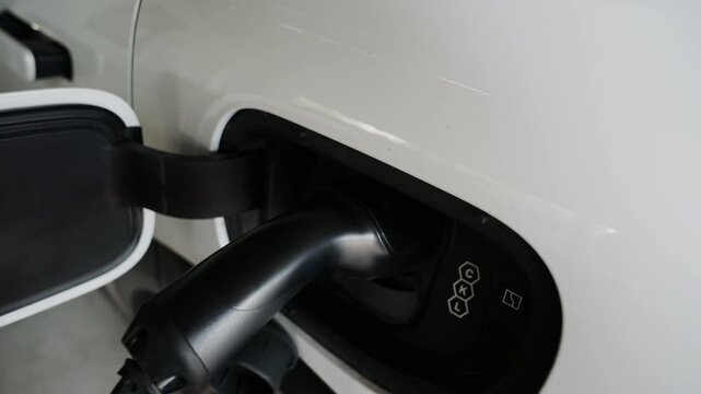 4K slow motion person charging electric car at home.	
