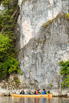 Canada, BC, Bowron Lakes Provincial Park.  Canoe at the base of a granite cliff on the edge of Swan Lake.