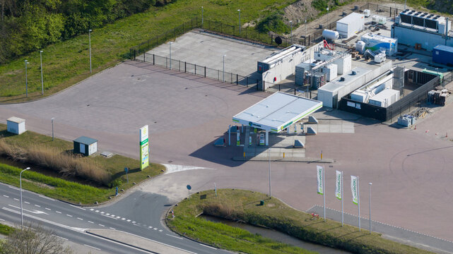 Oude-Tonge, Netherlands - 25 April 2026: Aerial view of the Rolande LNG filling station featuring fuel pumps under a white canopy, storage tanks, and industrial equipment surrounded by paved areas.