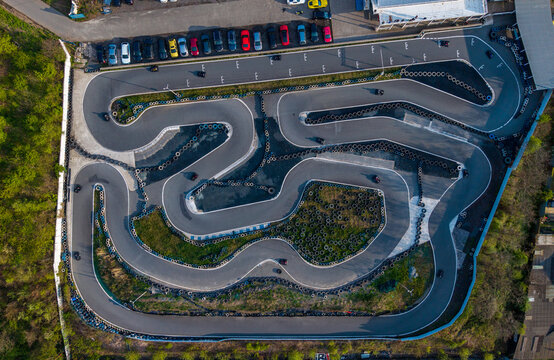 Prague, Czechia - 21 April 2026: Aerial view of KartPlanet go-kart track featuring winding asphalt turns, tire barriers, and a parking lot with cars.