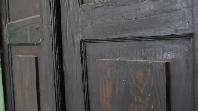 Close-up cinematic footage of a hand knocking on a wooden door with natural dramatic lighting. Suitable for concepts of waiting, arrival, communication, opportunity, home visit, suspense, and storytel