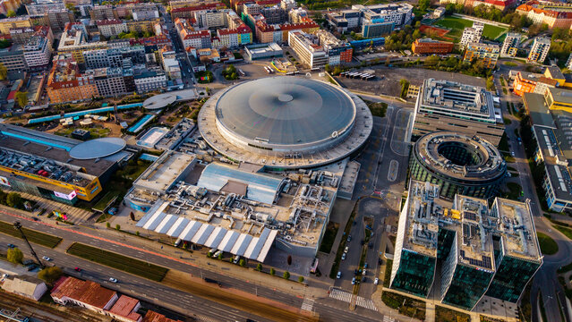 Cheskomoravska, Czechia - 21 April 2026: Aerial view of O2 arena surrounded by modern office buildings and residential blocks under clear sunlight.