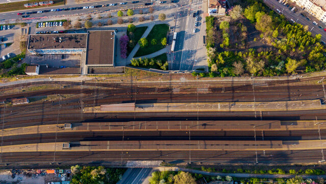 Praha, Czechia - 21 April 2026: Aerial view of the marshalling yard and railway tracks with platforms, urban buildings, and green trees under bright sunlight.