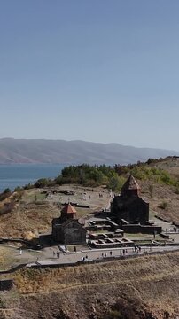 Vertical drone view of ancient monastery, Lake Sevan and surrounding hills, Armenia