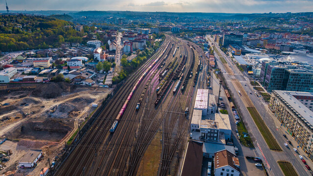 Prague, Czechia - 21 April 2026: Aerial view of a marshalling yard with freight trains on multiple tracks, industrial buildings, and the urban skyline in the background.