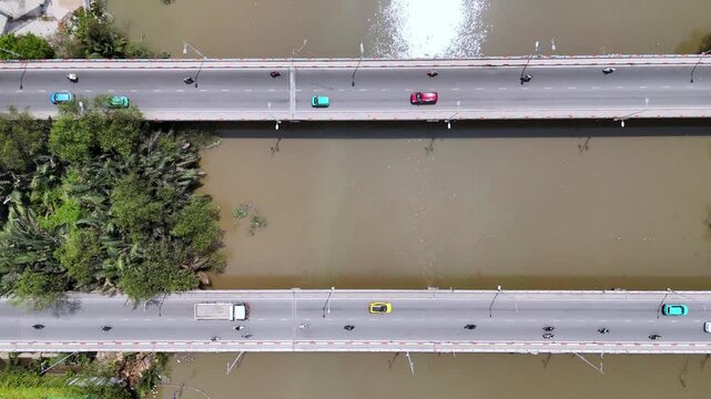 Top-down aerial drone view of traffic flowing across parallel bridges over a river in Ho Chi Minh City.