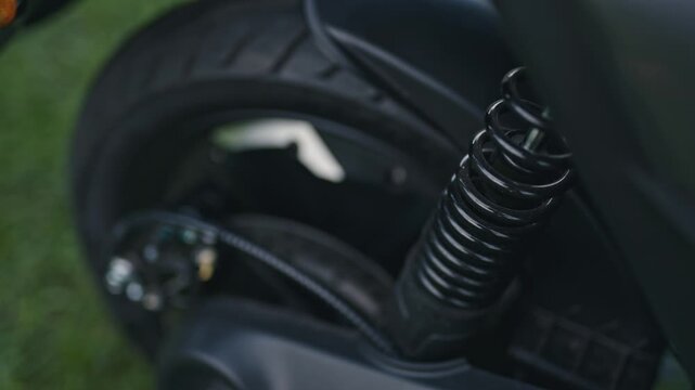 Footage of an electric scooter suspension system. Shows shock absorber, spring detail, and mechanical components designed for stability and smooth riding.
