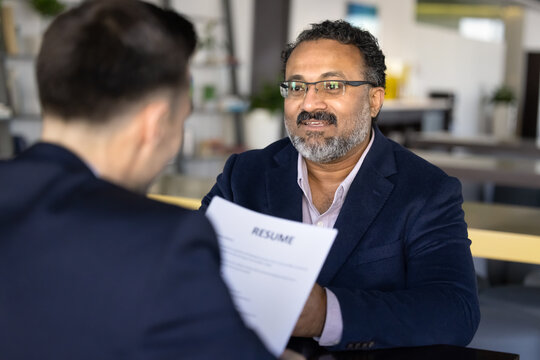Applicant sitting in front of HR manager holds resume paper, interviewing middle-aged vacancy candidate in company office. Self-presentation, human resources, employment, new job position opportunity