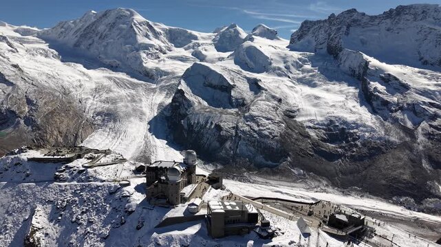 Aerial flyover above the observatory of Gornergrat in Zermatt, Switzerland with a view revealing the Gorner glacier on a snowy autumn day in the Swiss Alps