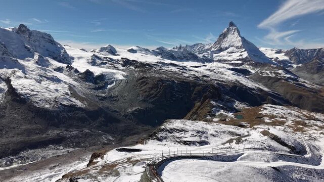 Aerial flyover over the Gornergrat railway in Zermatt, Switzerland with a view of the Matterhorn on a snowy autumn day in the Swiss Alps