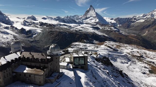 Aerial flyover over the observatory of Gornergrat in Zermatt, Switzerland with a view of the Matterhorn on a snowy autumn day in the Swiss Alps