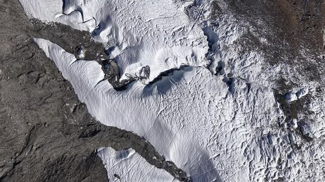 Aerial flyover over the Gorner glacier at Gornergrat in Zermatt, Switzerland with a pan up view from the icy crevasses up to the famous peaks of Dufourspitze and Monte Rosa
