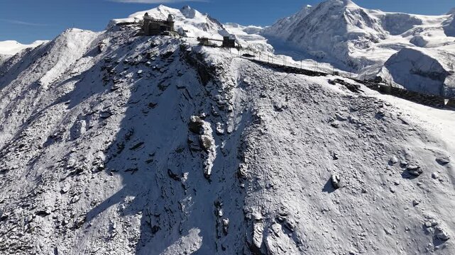 Aerial flyover over the observatory of Gornergrat in Zermatt, Switzerland with a view revealing the Gorner glacier on a snowy autumn day in the Swiss Alps