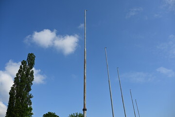 Obraz premium Row of Empty Flagpoles Against Clear Blue Sky
