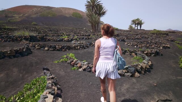 Woman walking through a volcanic vineyard in Lanzarote, Spain