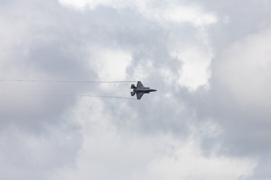 American 5th generation stealth fighter jet of the US Air Force performing aerial maneuvers in cloudy skies. Powerful modern military aircraft flying during aviation demonstration