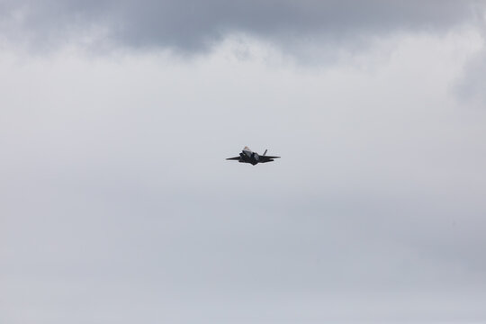 American 5th generation stealth fighter jet of the US Air Force performing aerial maneuvers in cloudy skies. Powerful modern military aircraft flying during aviation demonstration