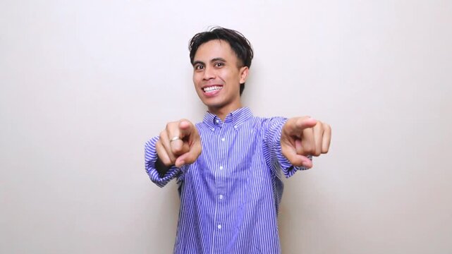 Excited handsome Asian man standing and pointing at camera inviting viewers to join, recruitment and advertising concept