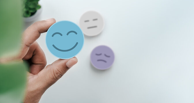 Hand holding blue paper cut happy smile face, Positive thinking, Mental health, World mental health day concept, Happy customer satisfaction feedback, Positive user experience rating service quality
