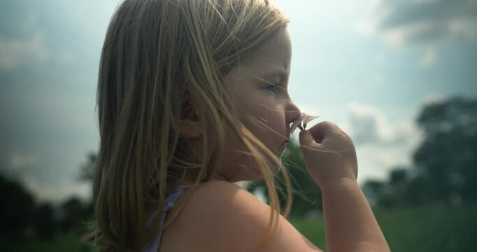 A child gently smells a flower, appreciating the simple beauty of nature. The moment feels quiet and intimate.