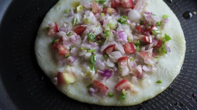 Indian chilla or uttapam prepared on black pan in kitchen