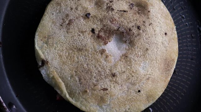 Indian chilla or uttapam prepared on black pan in kitchen