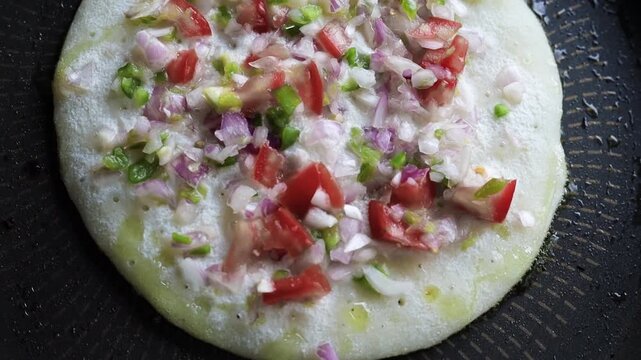 Indian chilla or uttapam prepared on black pan in kitchen